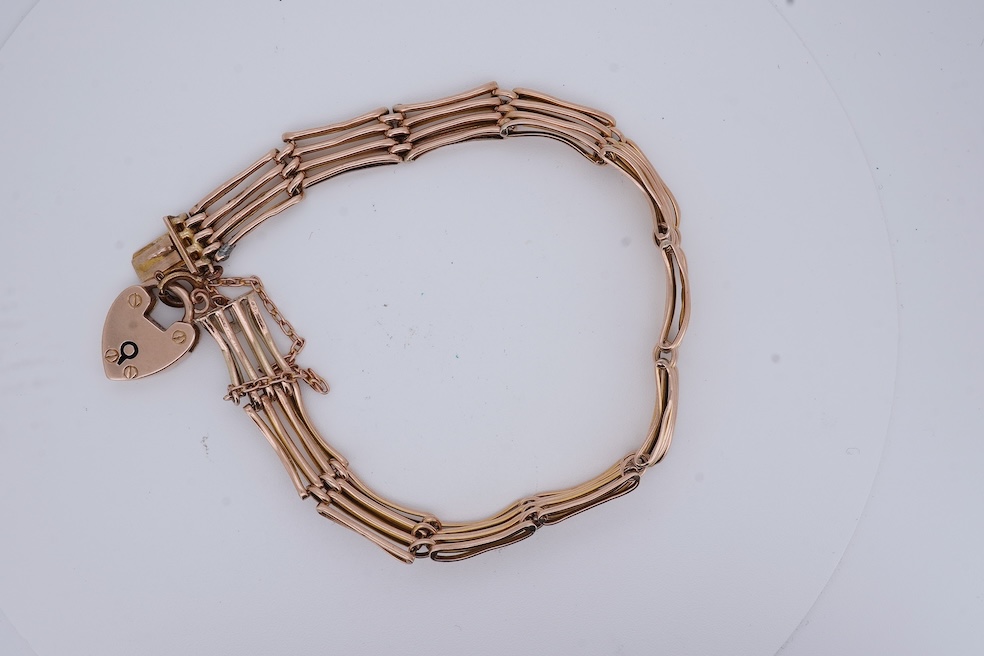 An early 20th century yellow metal gate link bracelet, with heart shaped padlock clasp on safety chain, stamped '9', approx. 18cm, 9.2 grams. Condition - poor